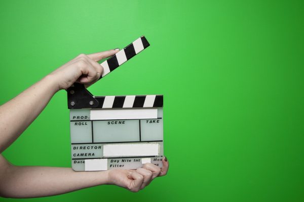 555电影资料核查员正在逐条比对公开页面上的影片上映信息，桌面摊开着笔记本与打印资料，画面呈现严谨细致的氛围